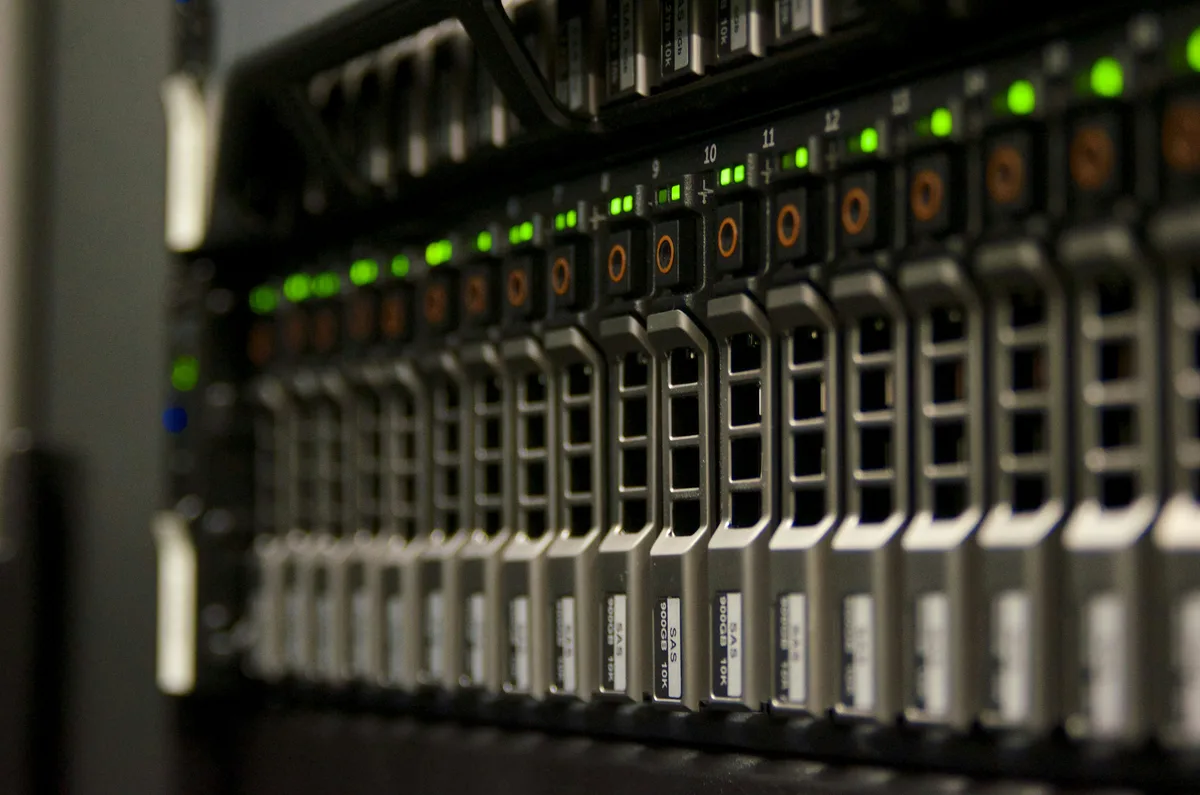 A darkened server rack seen head on, its stacked units marked by rows of small green status lights.
