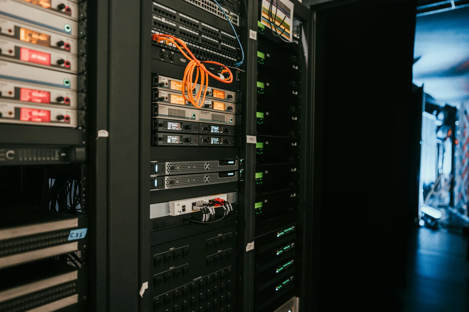 A row of rack-mounted servers in a dimly lit server room, front panels and cabling visible