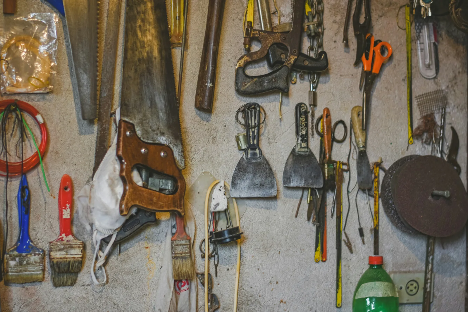 A pegboard wall densely covered with dozens of different hand tools hanging in rows, so many and so similar that no single one stands out.