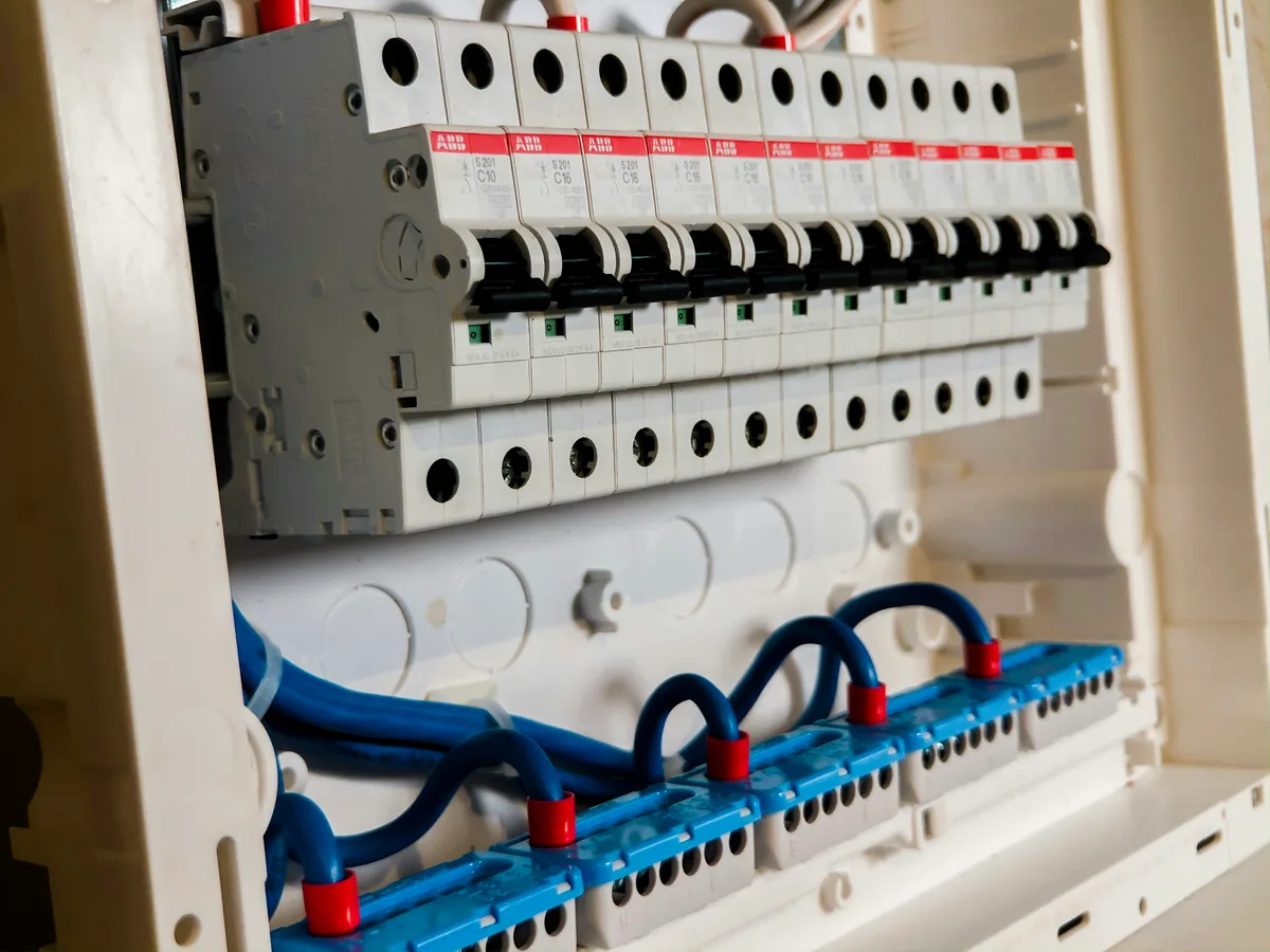 A row of white circuit breakers in an electrical panel, each an identical single switch that can be thrown independently of the others.
