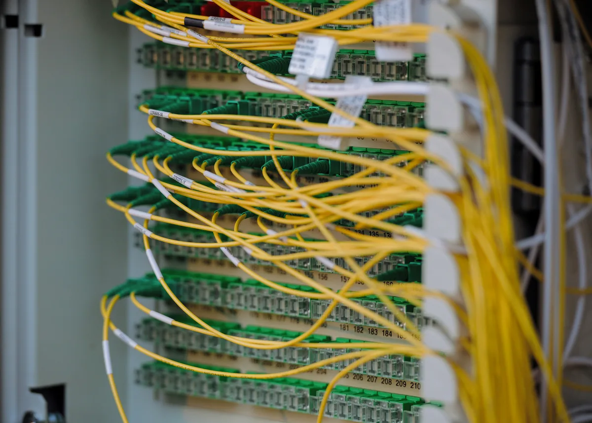 Yellow and green fibre optic cables running neatly into a dense row of ports.