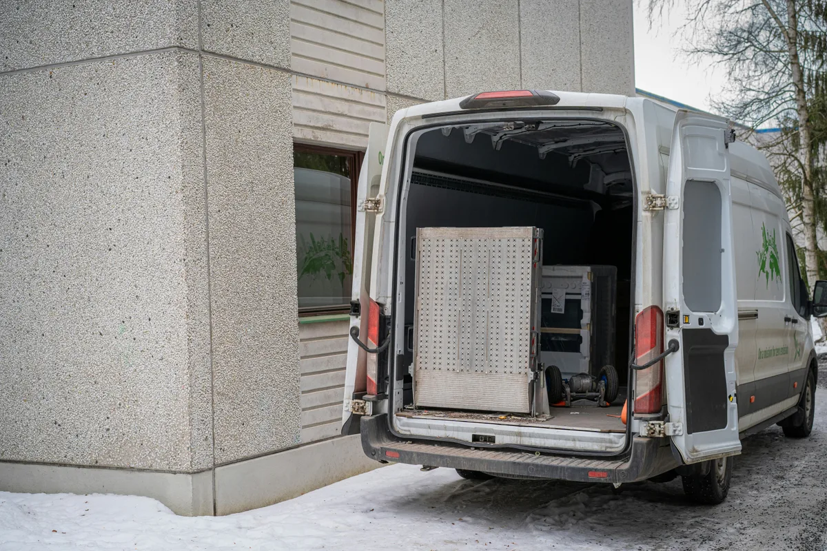 A delivery van parked with its rear doors swung open, the empty load space visible inside.